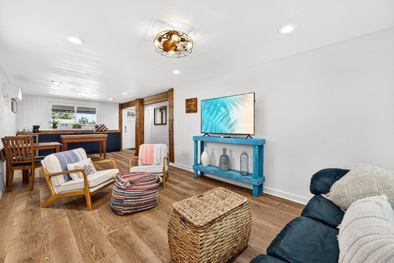 Sink into the plush seating and unwind in this bright, open living space designed for your comfort, with warm wood tones and charming coastal decor welcoming you home.