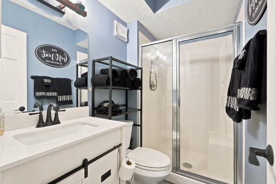You'll find fresh black towels neatly displayed and a bright, modern bathroom with a walk-in shower, sink vanity, and all the essentials for a comfortable stay.