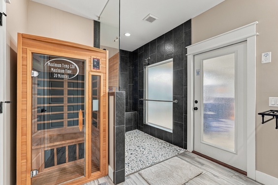 Step into your private wellness retreat with an infrared sauna and spacious walk-in shower featuring sleek black tile and pebbled flooring—perfect for unwinding after a day of exploring.