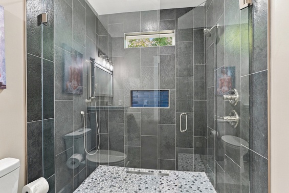 Step into your private spa-like shower, beautifully tiled in sleek grey stone. Multiple showerheads and a spacious walk-in design make every rinse feel indulgent and refreshing.