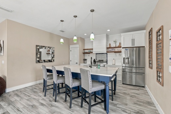 Gather around the bright, open kitchen island—your perfect spot for morning coffee or evening meals with crisp white cabinetry, modern appliances, and soft pendant lighting overhead.