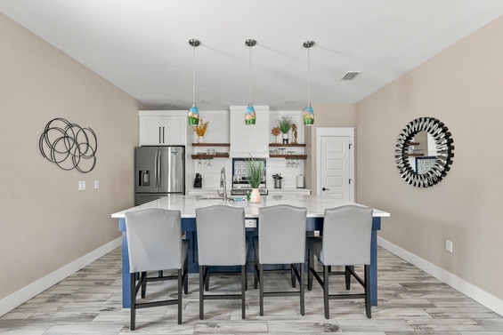 Gather around the spacious island with seating for eight, where modern pendant lighting and sleek white countertops set the stage for your shared meals and lively conversations.