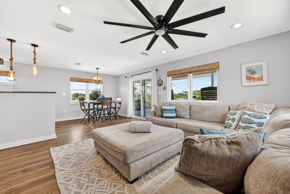 Relax in your bright, open living space with plush seating and a ceiling fan keeping you comfortable. Natural light pours through large windows, while the dining area invites meals with views of the lush surroundings.