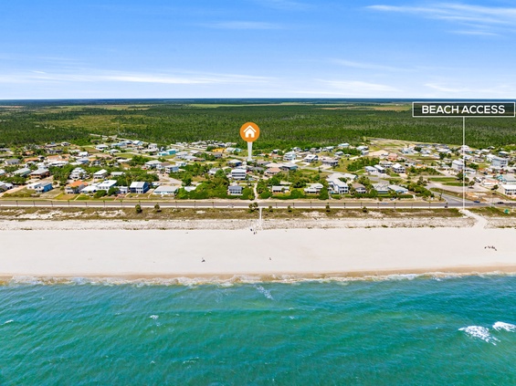 Aerial view of a beachfront community with direct access to pristine sandy shores and turquoise waters, featuring a residential coastal neighborhood.