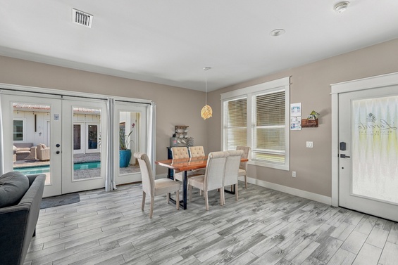 Gather around this inviting dining space where warm wood tones meet modern comfort. Through the glass doors, your private pool awaits—perfect for easy indoor-outdoor living and memorable meals together.