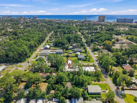 Aerial view of a coastal neighborhood with the property nestled among lush greenery, just a short distance from sandy beaches and the sparkling Gulf waters.