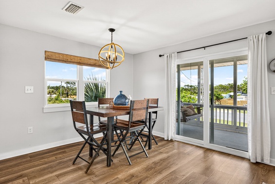Gather around this inviting dining table where natural light streams through large windows and doors. Step outside to your private balcony overlooking lush greenery and palm trees.
