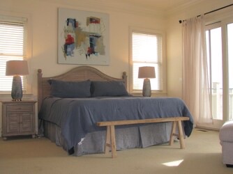 Sink into plush bedding and wake to sunlight streaming through expansive windows. Your peaceful retreat features elegant nightstands, warm lamps, and a cozy seating bench at the foot of your bed.