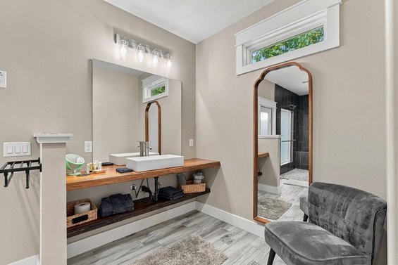 Your private bathroom retreat features a sleek vessel sink on warm wood counters, soft lighting, and a stylish seating nook—everything you need to start each day refreshed.