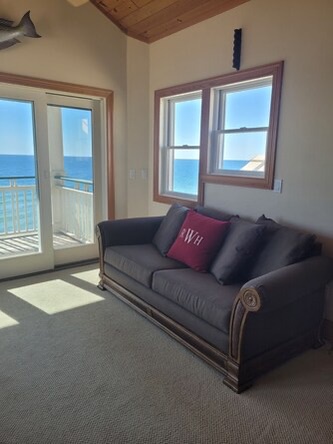 Your oceanfront living room frames endless blue horizons through floor-to-ceiling windows. Soft natural light fills the space where you can unwind and watch waves dance beyond your private balcony.