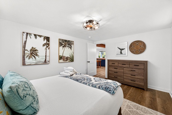 Drift off in this bright, coastal bedroom with plush bedding, tropical artwork, and a ceiling fan to keep you cool. Your oceanside retreat awaits through that door.