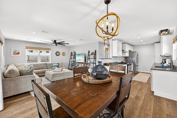 You'll love gathering in this beautiful open-plan space where coastal charm meets modern comfort. Sunlight pours through the windows, highlighting the rich wood floors and inviting you to unwind on the plush sectional or share meals at the rustic dining t
