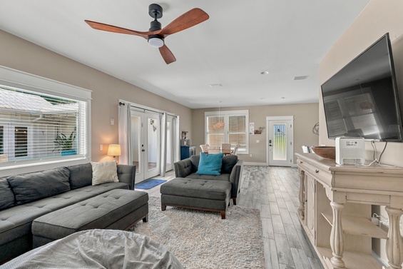 Unwind in your spacious living area, featuring plush seating, warm coastal tones, and French doors that welcome natural light and lead to your private outdoor space.