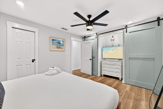 Relax in this serene coastal bedroom with crisp linens, charming beach-inspired decor, and a modern barn-door accent. The ceiling fan and ample storage ensure your comfort and convenience throughout your stay.