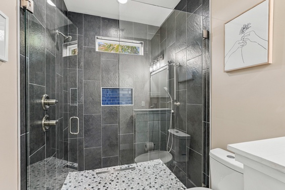 Step into your sleek, modern bathroom with a spacious walk-in shower featuring elegant dark tiling, dual fixtures, and a rainfall showerhead—your personal spa retreat awaits.