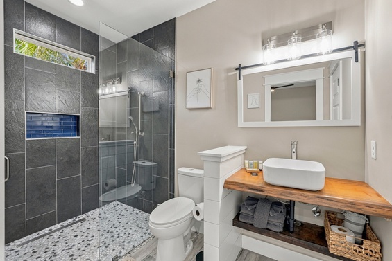 Step into your private spa-like retreat with sleek gray tile, a spacious walk-in shower, and a charming barn-door mirror that brings modern comfort to your daily routine.