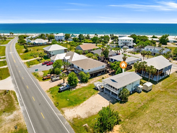 Aerial view of beachfront vacation homes nestled along the Gulf Coast, offering serene coastal living just steps from pristine white sand beaches and turquoise waters.