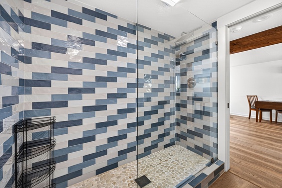 Step into your beautiful walk-in shower featuring eye-catching blue and white tiles, a smooth pebble floor beneath your feet, and plenty of space to refresh and unwind.