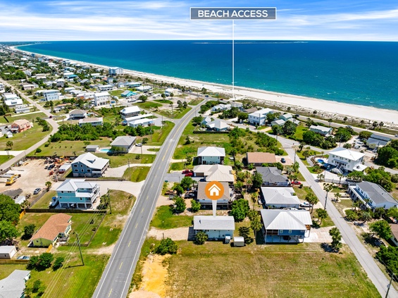 Aerial view of a coastal neighborhood with direct beach access just steps away. The property sits in a residential area near pristine white sand beaches and turquoise Gulf waters.