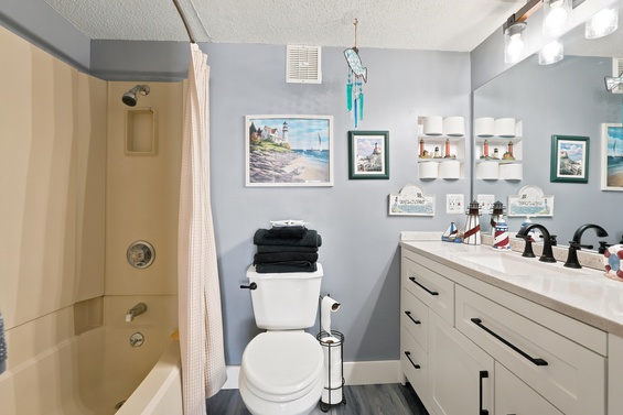 Step into your refreshed coastal bathroom, where light blue walls meet cheerful lighthouse artwork and nautical charm. Fresh linens and a spacious vanity make your morning routine feel like a seaside retreat.