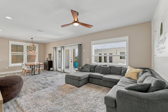 Settle into the plush sectional and unwind in your open, airy living space—sunlight pours through the windows while the ceiling fan keeps you cool.