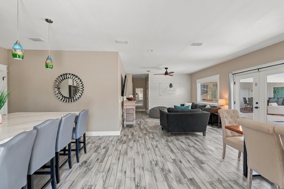 Spacious open living and dining area with modern coastal charm, plush seating, large dining table, stylish pendant lighting, and serene décor.