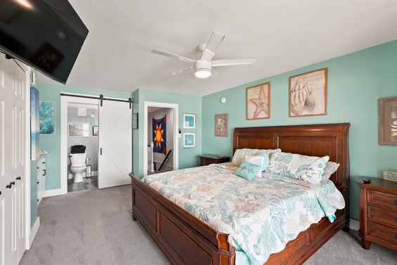 Sink into a plush bed with coastal-themed linens and beach art adorning calming aqua walls. Your private barn door bathroom and ceiling fan keep you comfortable after a day of adventure.