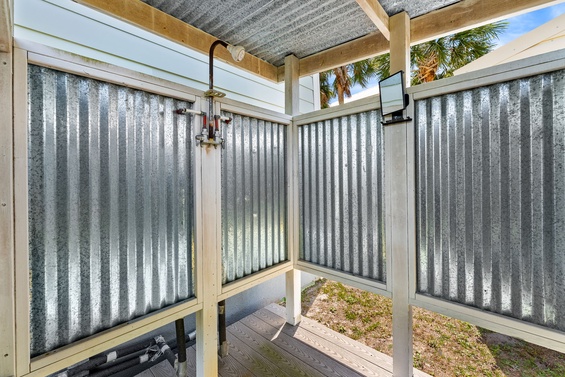 Rinse off the beach sand in this rustic outdoor shower framed with corrugated metal walls, complete with warm water and open-air access to sunny skies and palm trees overhead.