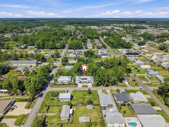 Aerial view of a residential neighborhood with tree-lined streets and green spaces, showing the property's peaceful setting within the surrounding area.