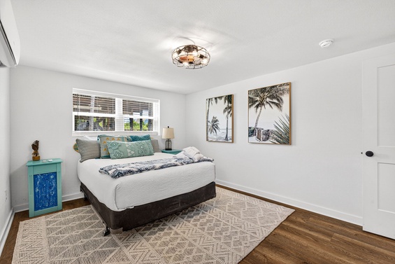 Your bright bedroom features a plush queen bed dressed in crisp white linens, coastal-inspired artwork, and a vintage-style ceiling fan to keep you comfortable year-round.