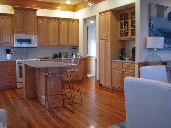 Your spacious kitchen features warm wood cabinetry, a central island with seating, and gleaming hardwood floors—perfect for preparing meals and gathering together during your stay.
