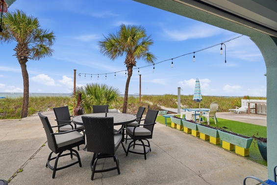 Dine al fresco at your covered patio table, where palm trees sway, string lights glow at dusk, and the beach lies just steps beyond the dunes, inviting you to unwind.