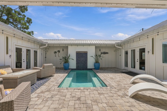 A serene private courtyard with a sparkling pool surrounded by comfortable lounge seating and inviting doorways opening into your retreat.