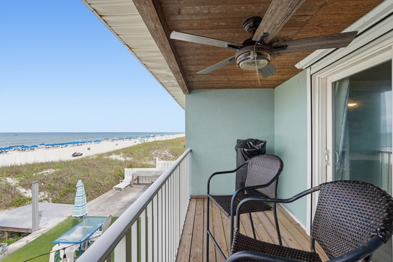 A covered beachfront balcony overlooking sandy shores and gentle waves. The property sits directly on the coast, offering convenient beach access just steps away.
