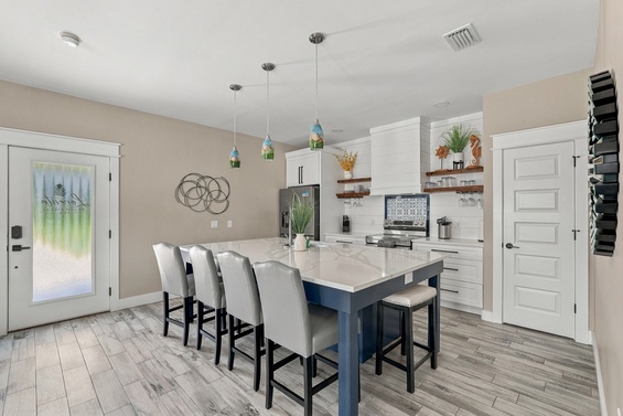 Step into your bright, open kitchen and dining area where coastal-style pendant lights cast a warm glow over the spacious marble island—perfect for morning coffee or evening conversations.