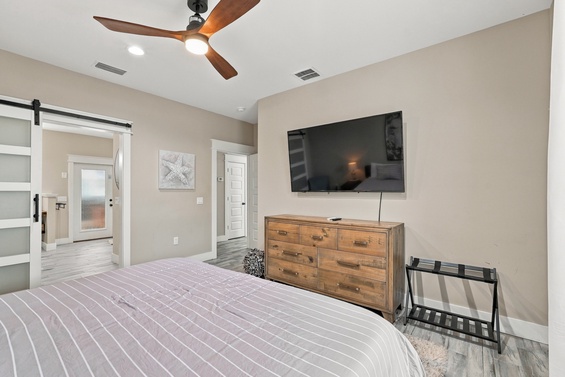Your serene bedroom retreat features modern barn doors, a stylish wooden ceiling fan, and a cozy private ensuite just steps away. Relax in this peaceful space designed for your comfort.