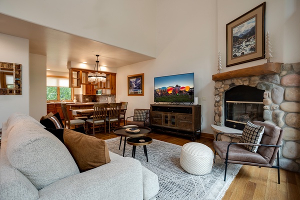 Settle into your cozy living room with a stone fireplace, plush seating, and an open flow to the dining area and kitchen—perfect for relaxing after mountain adventures.