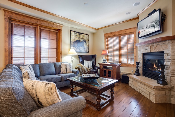 Sink into plush seating by your glowing fireplace, surrounded by warm wood accents and mountain charm—your cozy retreat after a day of adventure.