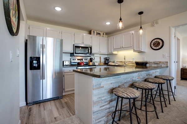 Your modern kitchen awaits with gleaming appliances, ample counter space, and a breakfast bar perfect for your morning coffee or casual meals together.