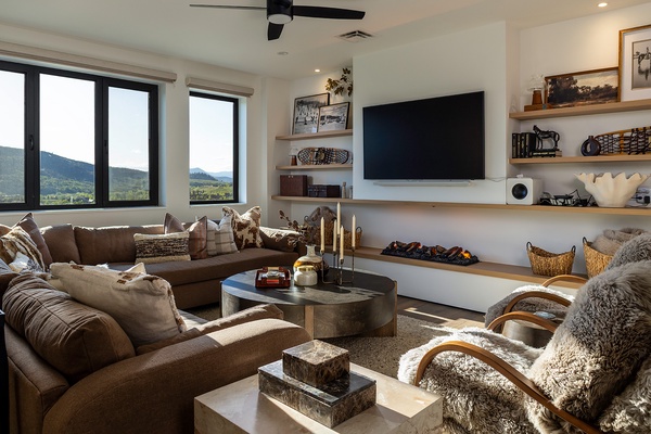 Sink into plush seating and soak in stunning mountain vistas through floor-to-ceiling windows. Your cozy retreat features a stylish fireplace, smart TV, and warm textures that invite you to unwind in comfort.