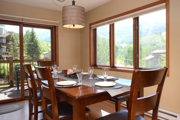 Gather around your dining table where mountain vistas frame every meal. Natural light fills this welcoming space, inviting you to linger over breakfast as the morning sun illuminates the peaks beyond.