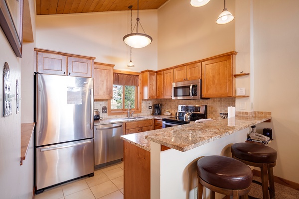 Your fully equipped kitchen features granite countertops, stainless steel appliances, and a breakfast bar—perfect for preparing meals and gathering with loved ones in this warm, inviting space.
