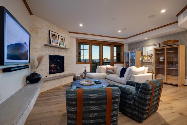 Curl up in your spacious living room with plush seating around the fireplace, where modern comfort meets rustic charm. Enjoy movie nights on the big screen or watch stunning views unfold through expansive windows.