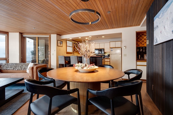 Gather around this stunning table beneath warm wood ceilings—your elegant dining space flows seamlessly into a fully-equipped kitchen, perfect for sharing meals and memories.