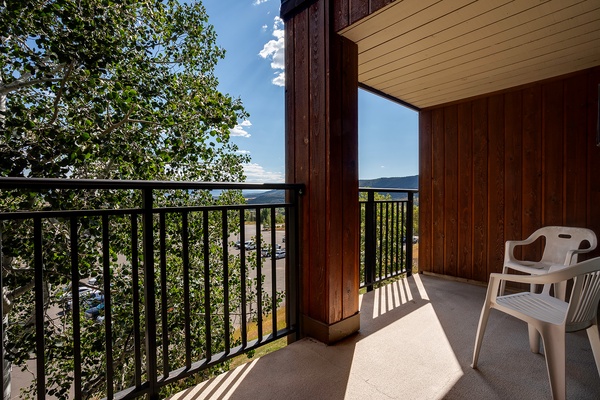 A private balcony framing peaceful tree-lined views and distant hills, perfect for savoring your morning coffee in the fresh mountain air.