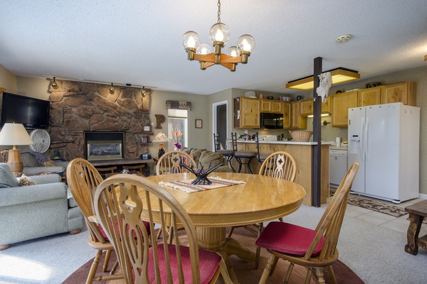 Gather around the dining table with rustic charm framing your mountain retreat. The stone fireplace and open layout create a cozy, inviting space perfect for your group getaways.