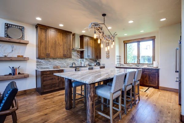 Gather around the spacious marble island where rustic elegance meets modern comfort. Rich wood cabinetry, gleaming countertops, and charming antler-inspired lighting create your perfect mountain retreat kitchen.