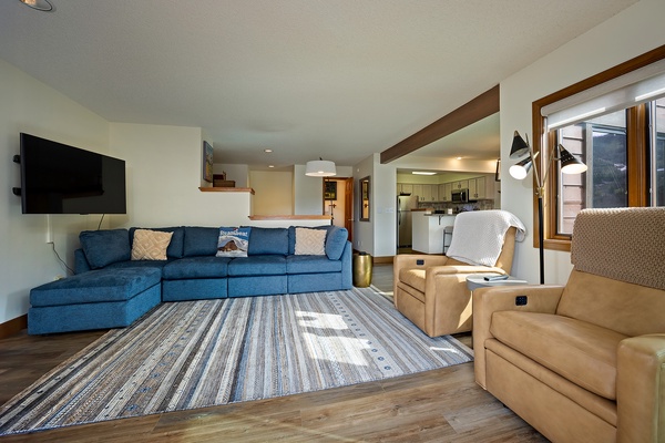 Sink into the plush blue sectional and unwind in this bright, open living space where mountain views greet you through large windows. The fully equipped kitchen beckons just beyond.