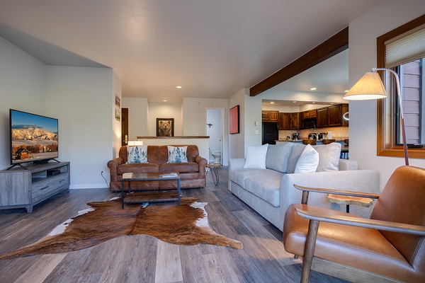 Relax in your open-concept living space featuring vaulted ceilings with rustic beams, plush seating for everyone, and a fully equipped kitchen ready for your culinary adventures.