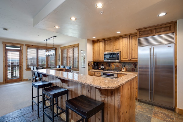 Your fully-equipped chef's kitchen features granite counters, stainless appliances, and a breakfast bar overlooking mountain views—perfect for morning coffee or group gatherings.